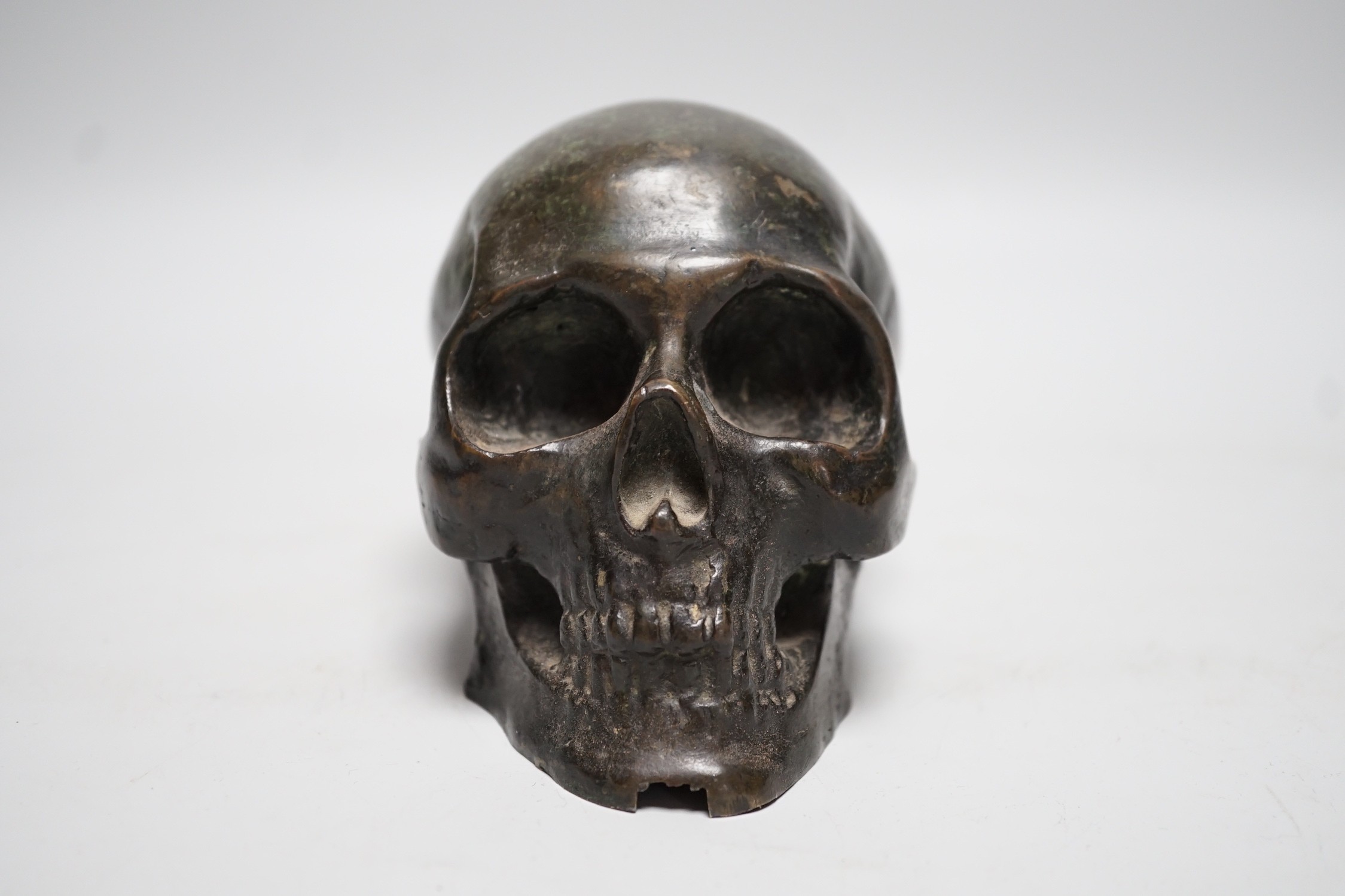 A bronze model of a skull, once part of a larger piece. 13cm deep